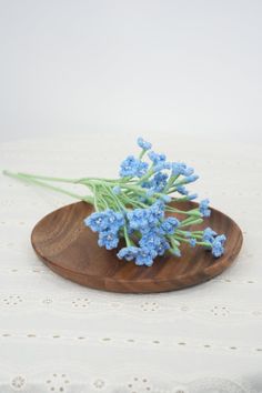 small blue flowers sitting on top of a wooden plate