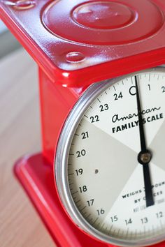 a red and white clock sitting on top of a wooden table