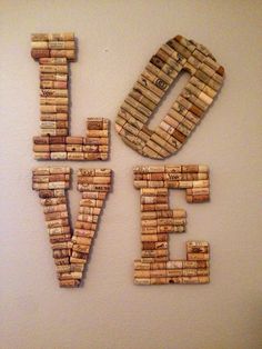 the word love spelled with wine corks on a white wall next to a clock