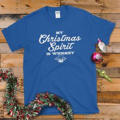 a t - shirt that says, my christmas spirit is whiskey on it next to ornaments