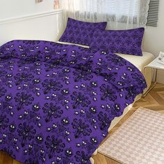 a bed with purple sheets and pillows in a room