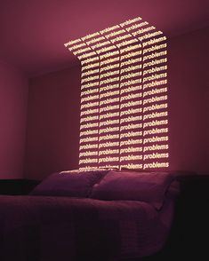 a bed with purple sheets and pillows in a room that is lit up by lights