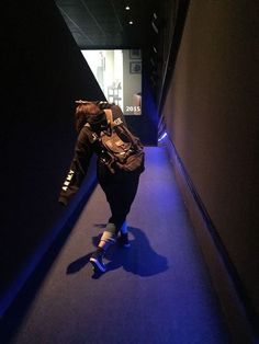 a person walking down a dark hallway with a backpack on their back and one foot in the air