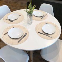 the table is set with white plates and place settings for four people to eat at