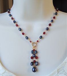 "You really can't go wrong with this classic necklace. It is so elegant and versatile, perfect for all seasons. This lariat style necklace combines luminous baroque black pearl with red garnet crystals. It features a decorative infinity circle plated in 24 karat gold. This necklace measures 16\" in length, with 2 inches extension. The pendant-tassel measures 2\" in length. This stunning necklace is unique, feminine and eye-catching, Perfect for anyone that wants to make a statement or to wear to Elegant Wire Wrapped Dangle Beaded Necklaces, Elegant Red Lariat Necklaces, Elegant Red Lariat Necklace, Elegant Beaded Dangle Necklaces With Lobster Clasp, Elegant Beaded Dangle Necklace With Lobster Clasp, Elegant Red Wire Wrapped Necklace, Ruby Choker, Lariat Style Necklace, Choker Handmade