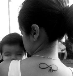 a woman with a tattoo on her back holding a baby