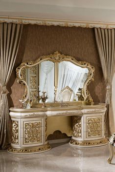 an ornate gold and white dressing table in a room with curtained drapes on the windows