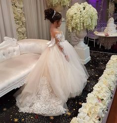 a woman in a wedding dress standing next to a white couch with flowers on it