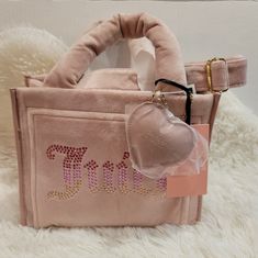 This Juicy Couture Dusty Blush Big Spender Mini Tote Is Perfect For Any Occasion, Whether You're Traveling Or Just Going About Your Daily Routine. It Features A Magnetic And Button Closure, With A Pink Velour Handle/Strap And Gold Hardware. The Bag Charm Adds A Touch Of Fun To This Stylish Tote, Which Has A Beige Fabric Lining And Measures 10 Inches In Width, 8 Inches In Height, And 5 Inches In Depth. The Tote Is Made Of Velour And Has A Dusty Blush Exterior Color, With A Lining Color Of Beige. Dusty Blush, Juicy Couture Bags, Beige Fabric, Functional Accessories, Mini Tote, Daily Routine, Juicy Couture, Gold Hardware, Bags Handbags