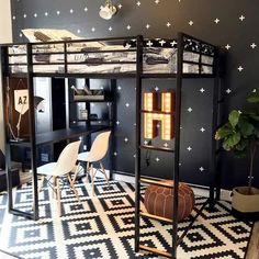 a loft bed with black walls and white stars on the ceiling is next to a desk