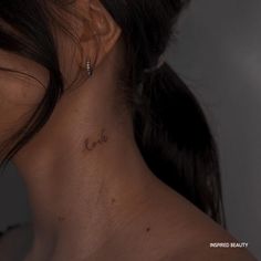 the back of a woman's neck has a small tattoo that reads love on it