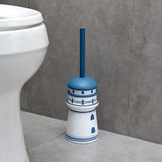 a white toilet sitting next to a blue and white vase on the ground in front of a gray wall