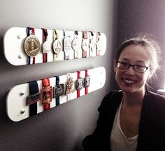 a woman standing in front of a wall with several medals hanging on it's sides