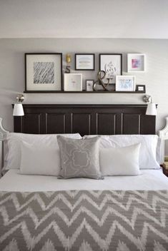 a bed with white sheets and pillows in a bedroom next to pictures on the wall