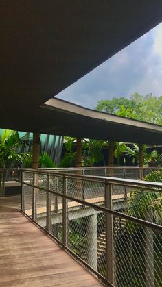 the walkway is lined with trees and plants, along with a metal railing that leads to an outdoor area