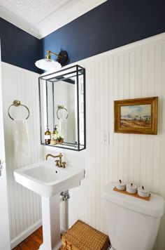 a white toilet sitting next to a sink in a bathroom under a mirror above it