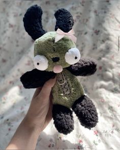 a hand holding a small stuffed animal with ears on it's head and nose