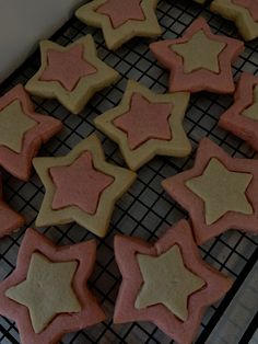 some cookies are cooling on a rack with pink and yellow stars in the shape of stars