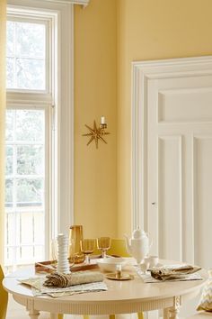 a dining room with yellow walls and white furniture