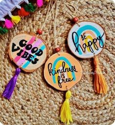 three hand painted wooden earrings with tassels on top of a woven place mat