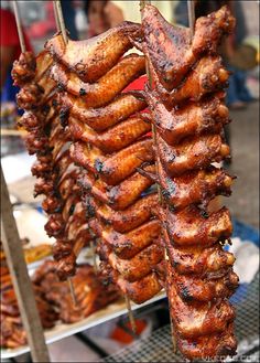 several skewers of meat are being cooked on the grill at an outdoor market