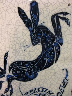 a blue and white tile with an image of a lizard on it's back