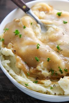 a white bowl filled with mashed potatoes covered in gravy