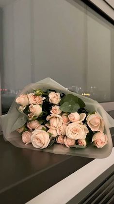 a bouquet of pink roses sitting on top of a window sill