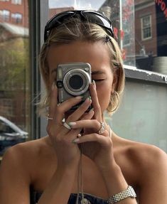 a woman taking a selfie in front of a window with her camera up to her face