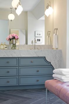 a bathroom with marble counter tops and blue drawers, along with white towels on the floor