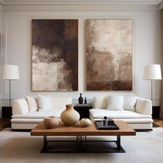 a living room with two paintings on the wall and a coffee table in front of it