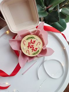 a decorated cookie sitting on top of a white plate next to a red and white ribbon