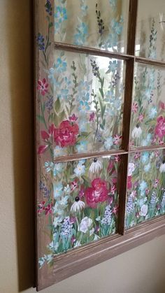 an old window with flowers painted on the glass is shown in front of a wall