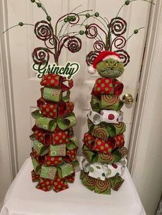 two green and red christmas decorations sitting on top of a white table