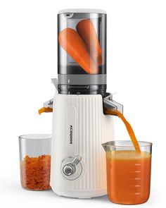 an orange juice being poured into a blender with carrots on the top and bottom