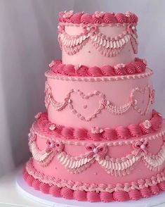 a three tiered pink cake with hearts on it