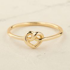 Our 14K Gold Twisted Heart Knot Ring is the epitome of elegance and heartfelt symbolism. This exquisite piece is carefully handcrafted from real 14K solid gold, ensuring both quality and luxury. The ring features a unique heart knot design, created from twisted gold wire, measuring 6.25 mm by 6.90 mm. This delicate yet striking design makes the ring a versatile piece, suitable for everyday wear or special occasions. Available in your choice of gold, rose gold, or white gold, this ring caters to Heart Knot Ring, Gold Knot Ring, Twisted Heart, Heart Knot, Love Knot Ring, Friendship Rings, Knot Design, Knot Ring, Christmas Snacks