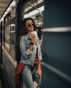 a woman leaning on the side of a train holding a drink