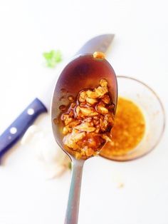 a spoon full of food sitting on top of a white table next to a knife