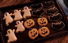 there are many decorated cookies in the tray on the table, including ghost and pumpkins