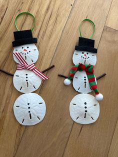 two snowmen made out of toilet paper sitting on top of a wooden floor next to each other