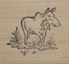 a wooden stamp with a cow standing in the water on it's front side