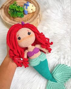 a crocheted little mermaid doll sitting on top of a white furnishing