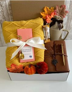 a gift box filled with books, coffee mug and autumn leaves on top of it