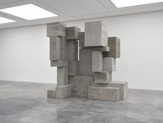 an abstract concrete sculpture sitting in the middle of a room with white walls and ceilings