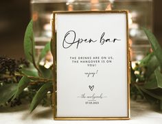 an open bar sign sitting on top of a table next to some leaves and candles