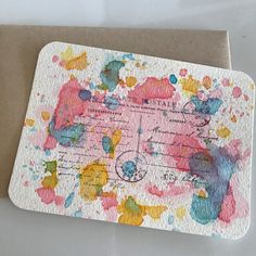 a piece of paper with paint splattered all over it on top of a card