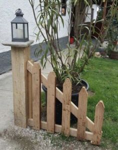 a wooden fence with a potted plant next to it and a lantern on top