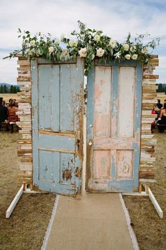 an old door is decorated with flowers and greenery for a rustic outdoor wedding ceremony