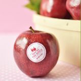 an apple sitting on top of a table next to a bowl filled with red apples